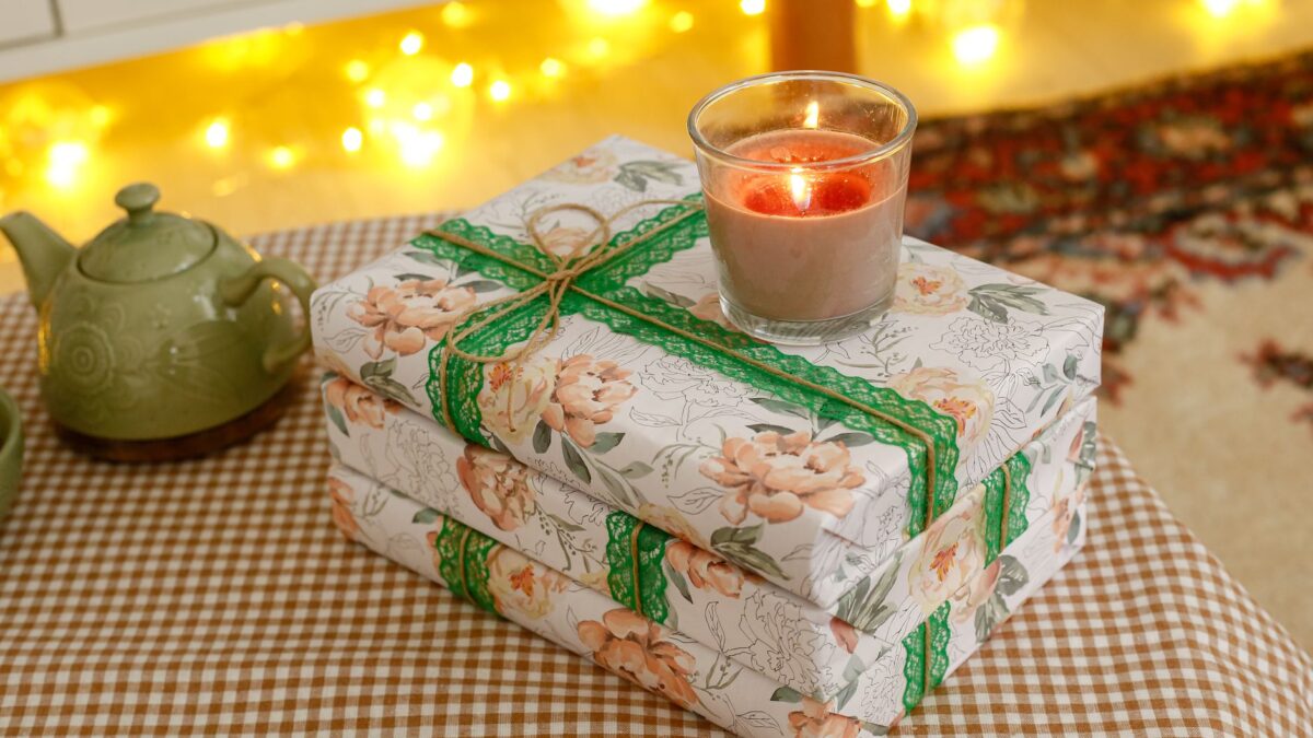 Eingepackte Geschenke neben einem Stapel Bücher in warmem Licht