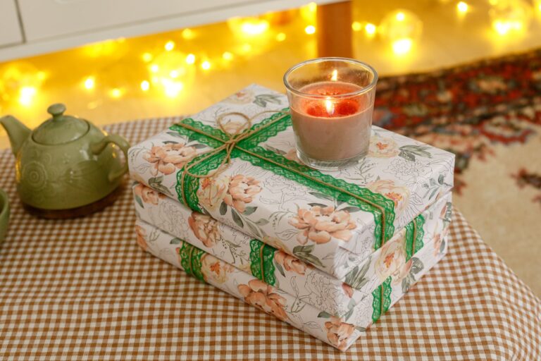 Eingepackte Geschenke neben einem Stapel Bücher in warmem Licht