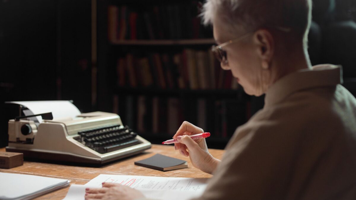 Manuskriptseiten mit Brille und Stift auf einem Schreibtisch