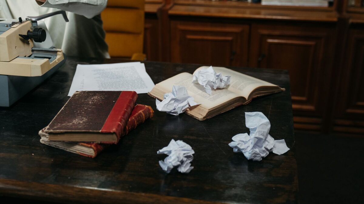 Manuskriptseiten und Unterlagen auf einem Schreibtisch im warmen Licht