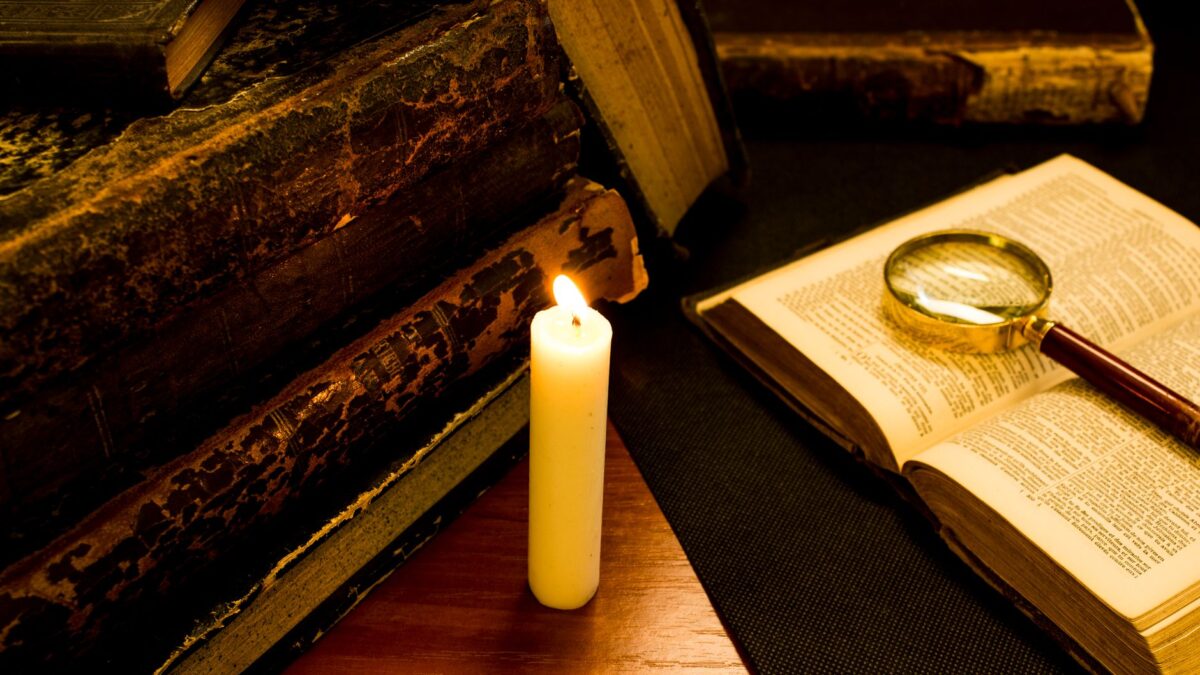 Aufgeschlagenes altes Buch bei Kerzenlicht – Redewendungen als Sprachgeschichte