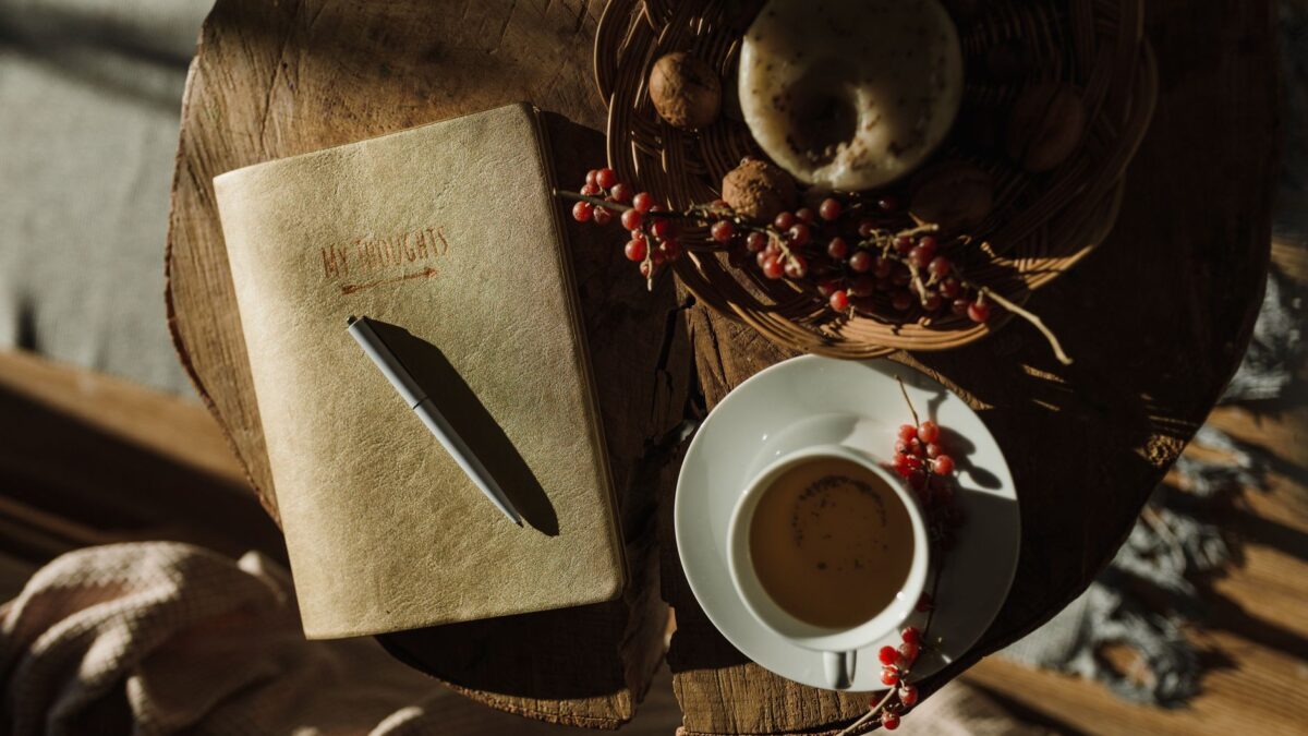 Notizbuch mit Stift und Kaffeetasse im warmen Morgenlicht