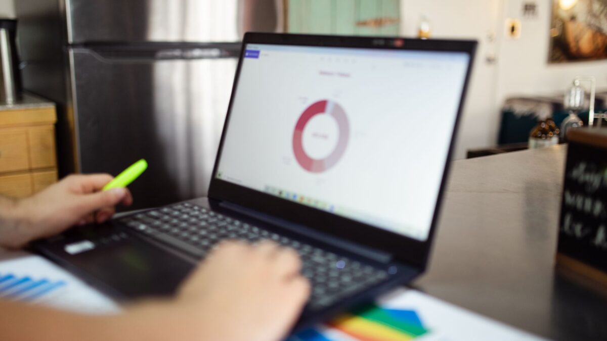 Laptop mit Analyse-Diagrammen auf dunklem Schreibtisch