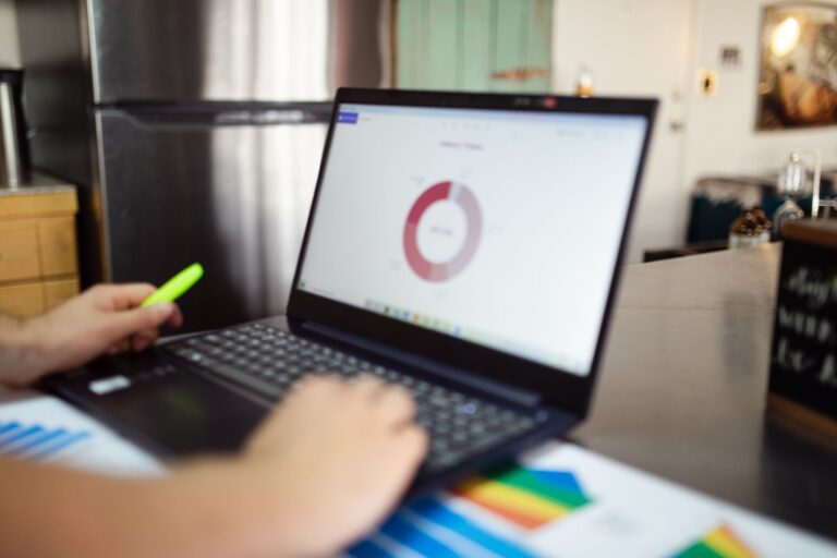 Laptop mit Analyse-Diagrammen auf dunklem Schreibtisch